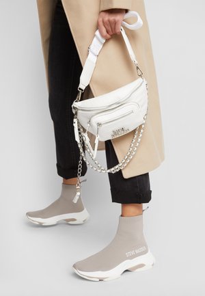 Sac à main texturé blanc avec deux compartiments zippés, quincaillerie en argent et une bandoulière en chaîne. Baskets de style chaussette grises avec des accents blancs.