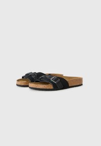 Sandales en suède noir avec des sangles tressées et des accents de boucle en argent. Semelle en liège et semelle extérieure noire pour le confort et le soutien.