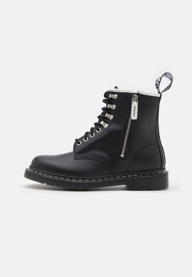 Bottine en cuir noir avec fermeture éclair latérale, lacets noirs, œillets métalliques et languette en tissu de marque à l'arrière.