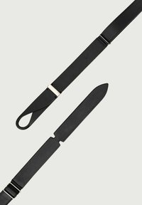 Cintura in pelle nera con design piatto e texture senza cuciture. Presenta un accento argenteo vicino alla fibbia e un'estremità della cinghia liscia a forma di lama.