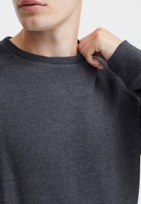 Grauer Sweatshirt mit rundem Ausschnitt und gerippten Akzenten am Kragen und an den Bündchen. Der Stoff wirkt weich und strukturiert. Legeres Design.