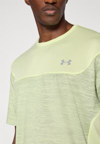 Αθλητική μπλούζα ανοιχτού πράσινου χρώματος με υφή στο κάτω μισό, ομαλό επάνω τμήμα και γκρι λογότυπο στο στήθος.