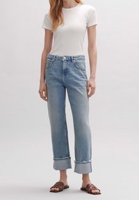 Jeans de denim azul claro con un corte relajado, que presentan una cintura alta, puños enrollados, diseño de cinco bolsillos y un cierre de botón.