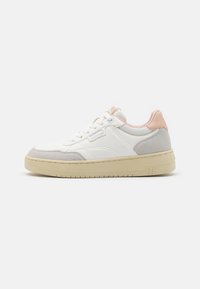 Zapatilla blanca con suela beige, presenta una parte superior de malla texturizada, detalles de ante en gris y una pestaña en el talón de color rosa. Diseño con cordones.