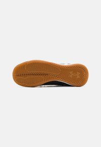 Sole di una scarpa da atletica nera con un motivo in gomma naturale testurizzata, caratterizzata da profonde scanalature per la trazione e un accento di logo bianco.