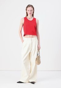 Piros, cropped tank top, fehér, magas derekú, széles lábú nadrág, fekete, hegyes orrú balerina cipők és egy szövött táska. Simává tettek, egyszerű vonalak és semleges színek.
