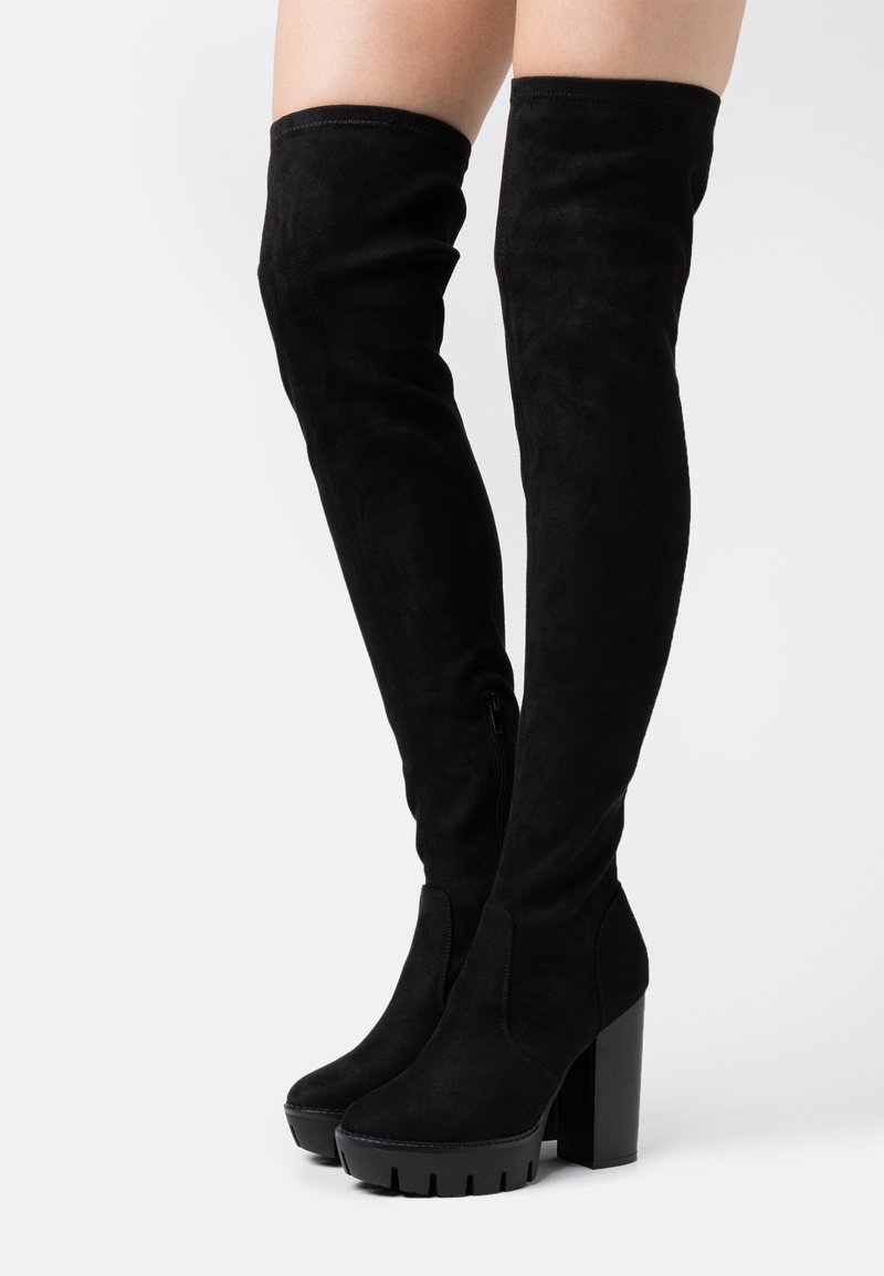 Černé semišové kozačky nad kolena, s robustním podpatkem, bočním zipem a hladkou texturou. Klasický design s přiléhavým střihem.