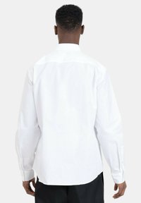 Witte langemouwen shirt met een opgerolde kraag en knopenmanchetten, met een gladde stofstructuur en een licht gebogen onderkant aan de achterkant.