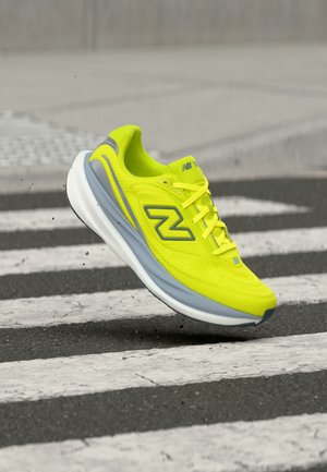 Chaussure de running New Balance jaune vif avec une semelle grise et blanche flottant au-dessus d'un passage piéton noir et blanc rayé.