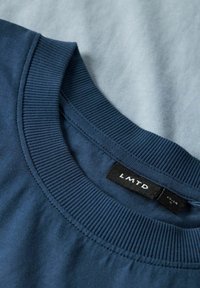 Marineblaues Baumwoll-T-Shirt mit geripptem Rundhalsausschnitt. Verfügt über ein Etikett mit "LMTD"-Markierung; glatte Textur, schlichtes Design, keine Muster.