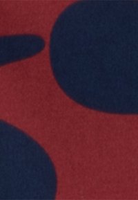 Gros plan abstrait d'une surface rouge avec de grandes formes ovales et circulaires bleu foncé.