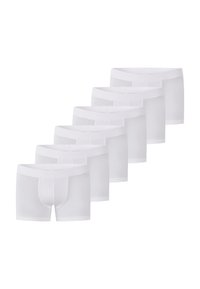 Vita bomullsboxershorts med en slät yta, kroppsnära passform och resårmidja. Sju par ordnade i en rad.