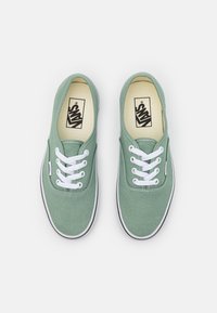 Mintgrüne Canvas-Sneaker mit weißen Schnürsenkeln, ikonisches Logo auf der Innensohle, kontrastierende schwarze Sohle und genähtes Detail entlang der Kanten.