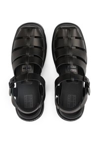 Svarte syntetiske sandaler med et vevd stroppe-design, justerbar spenne og flat såle. Har detaljer med merkenavn på sålen.