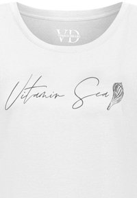 T-shirt bianco con testo "Vitamin Sea" in carattere corsivo, accompagnato da un design di conchiglia schizzato. Tessuto liscio e leggero.