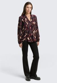 Long-sleeve blouse in dark purple with abstract pattern in light and dark shades. Features a deep V-neck and gathered cuffs.