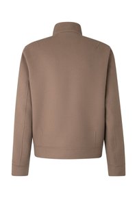 Bruine, op maat gemaakte jas van zachte stof. Heeft een hoge kraag en zijnaadzakken. Soepele textuur, strakke lijnen en een minimalistisch ontwerp.