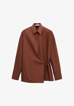 Brązowa koszula z długim rękawem, z ostrym kołnierzykiem, guzikami z przodu oraz detalem w postaci przewiązania po prawej stronie.