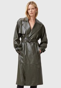 Cappotto trench in pelle verde oliva con vita cinturata, grande colletto e tasche. Texture liscia e design fino al ginocchio.