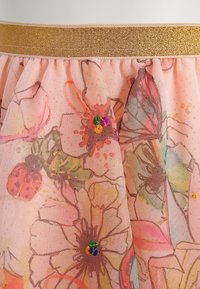 Lyserød tylstof med store pastelfarvede blomster- og sommerfuglemønstre, pyntet med små farverige perler og et guld elastikliv.