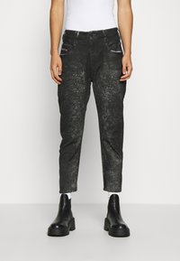 Pantalones de mezclilla negros con una textura desgastada, que cuentan con dos bolsillos frontales y acentos plateados. Diseño de pierna recta, recortados en el tobillo.