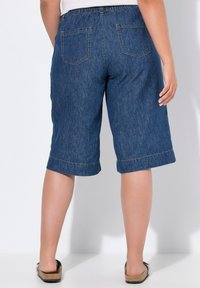 Bermudas de mezclilla, lavado medio, corte relajado con una cinturilla elástica, dobladillo enrollado y dos bolsillos traseros. Combinadas con sandalias planas.