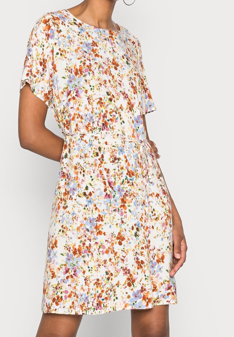 Robe fleurie en tissu léger, présentant des motifs orange, bleu et violet. Manche courte, encolure ronde et détail de taille avec cordon de serrage.