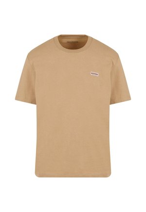 Bež pamukasta majica s kratkim rukavima, okruglim izrezom i malim izvezenim logotipom na lijevoj strani grudi. Glatka tekstura, ležeran dizajn.