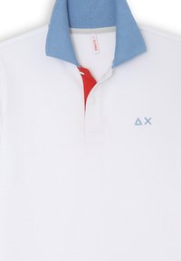 Polo bianco con colletto azzurro e accentuazione rossa sotto la bottoniera; presenta un piccolo logo blu sul petto. Materiale in cotone misto.