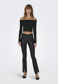 Czarny top typu off-the-shoulder z długim rękawem, zestawiony z czarnymi skórzanymi spodniami o wysokim stanie, z bocznymi rozcięciami i gładką fakturą.