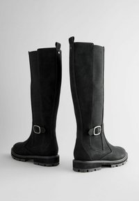 Czarne, do kolan sięgające buty wykonane z teksturowanego materiału, z okrągłym noskiem, masywną podeszwą oraz dekoracyjnym paskiem z srebrną klamrą.
