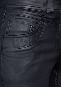 Svarta läderjeans med en klassisk femfickdesign, synlig sömnad och en slät textur med en lätt lyster.