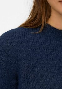 Mornarice plava pletena pulover s teksturiranim uzorkom, s dizajnom okruglog izreza i mekim, udobnim materijalom. Prikaz close-up tkanine.