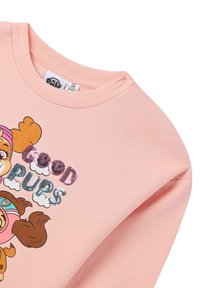 Sweatshirt rosa con scollatura a girocollo, caratterizzato da un'immagine di cani dei cartoni animati e la scritta "Buoni Cagnolini" in lettere colorate e decorate con paillettes.