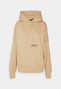 Sweatshirt beige à capuche avec une poche avant, des cordons de serrage et des détails de logo brodés. Il possède des poignets et un ourlet côtelés. Texture douce et lisse.