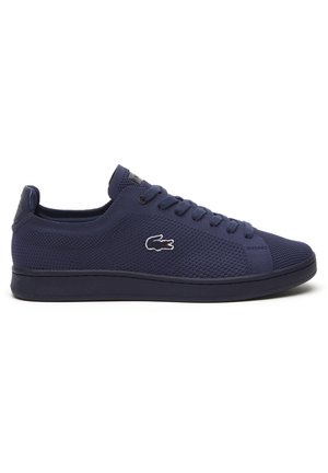 Marineblå lavtop sneaker med tekstureret stof, snørebånd foran, flad sål og en lille broderet krokodille-logo på siden.