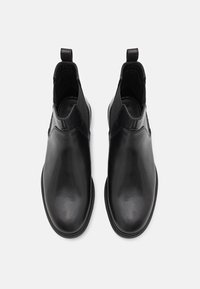 Bottes Chelsea en cuir noir avec une finition lisse, un bout arrondi, des panneaux latéraux élastiques et des languettes pour un enfilage facile.