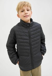 Jachetă puf cu fermoar, textură matlasată vertical și guler înalt. Prezintă un design ușor, ideal pentru stratificare.