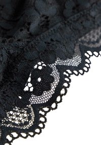 Tessuto in pizzo nero con motivi floreali intricati e bordi scallop. La texture è delicata e trasparente con un design geometrico dettagliato.