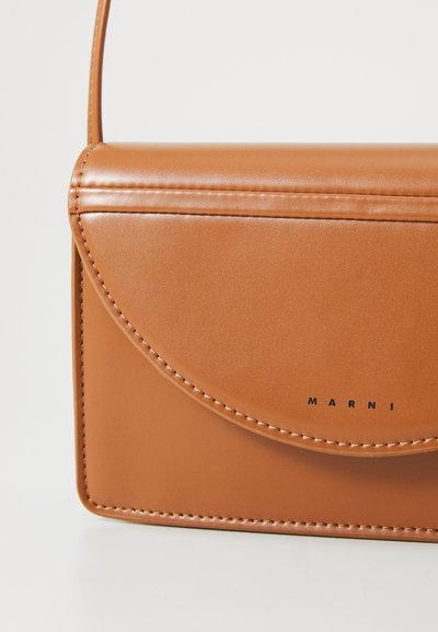 Geantă de umăr din piele maro, cu un capac curbat, cusături vizibile și un logo imprimat. Textură netedă și formă rectangulară compactă.
