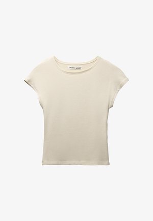 Tejszínszínű, rövid ujjú póló, puha pamutból készült. Kerek nyakkal és laza fazonnal rendelkezik, minimális varrási részletekkel.