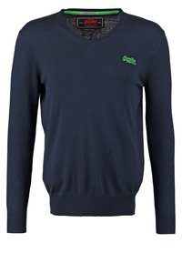 Granatowy sweter w serek z długimi rękawami, z prążkowanymi mankietami i dołem, wykonany z miękkiego materiału, z małym zielonym logo na klatce piersiowej.