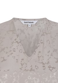 Blusa grigia chiaro con scollatura a V, motivi tonali intricati e una texture liscia e morbida. L'etichetta riporta "Soft Rebels," taglia S.