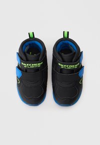 Par de ténis infantis Skechers S-Lights pretos e azuis com detalhes verdes e fechos de Velcro, vistos de cima sobre um fundo branco.