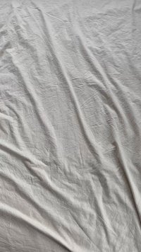 Tessuto grigio chiaro stropicciato con una consistenza morbida e una leggera lucentezza, disteso senza alcun motivo o accentuazione distintiva.