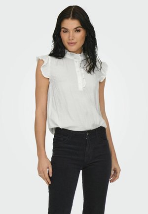 Vit, rynkad kortärmad blus med hög halsringning och knäppning fram, kombinerad med svarta, figurnära jeans. Mjuk textur, avslappnad design.