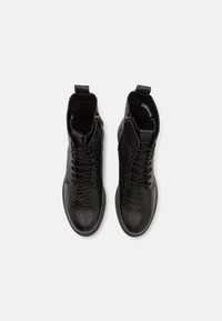 Bottines noires à motif crocodile texturé, avec une fermeture éclair sur le côté, un bout rond et une semelle en caoutchouc robuste.