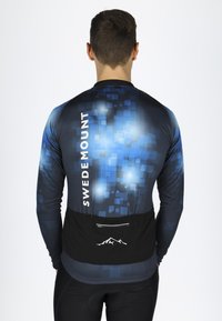 Långärmad atletisk tröja i blått och svart med pixelerat mönster, som har en ficka med dragkedja och "SWEDEMOUNT"-logotyp på baksidan.