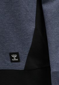 Mörkgrå sweatshirt med en slät yta och svarta detaljer. Visar en Hummel-logotyp på nedre vänstra sidan.