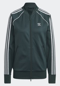 Dark green zip-up jacket made of smooth fabric, featuring white stripes along the sleeves, ribbed cuffs, and a small logo on the chest.